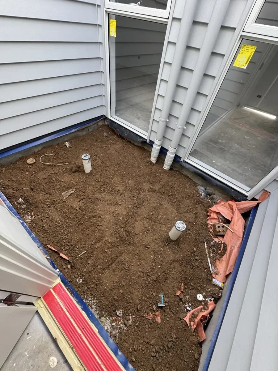 White PVC stormwater stub-up pipes roughed into the dirt against a new build wall with orange waterproofing membrane
